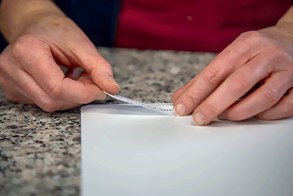 zwei Hände halten ein Etikett um es auf Papier zu kleben